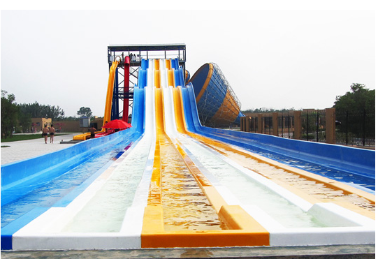 Toboggan aquatique multicolore à plusieurs voies pour parc aquatique | Toboggan de course à 4 voies sur tapis | Fabricant de toboggans arc-en-ciel en fibre de verre depuis 1994